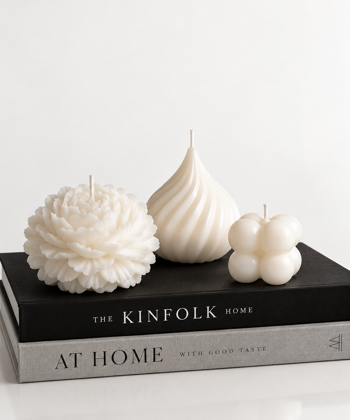 White sculptural candles styled on stacked design books